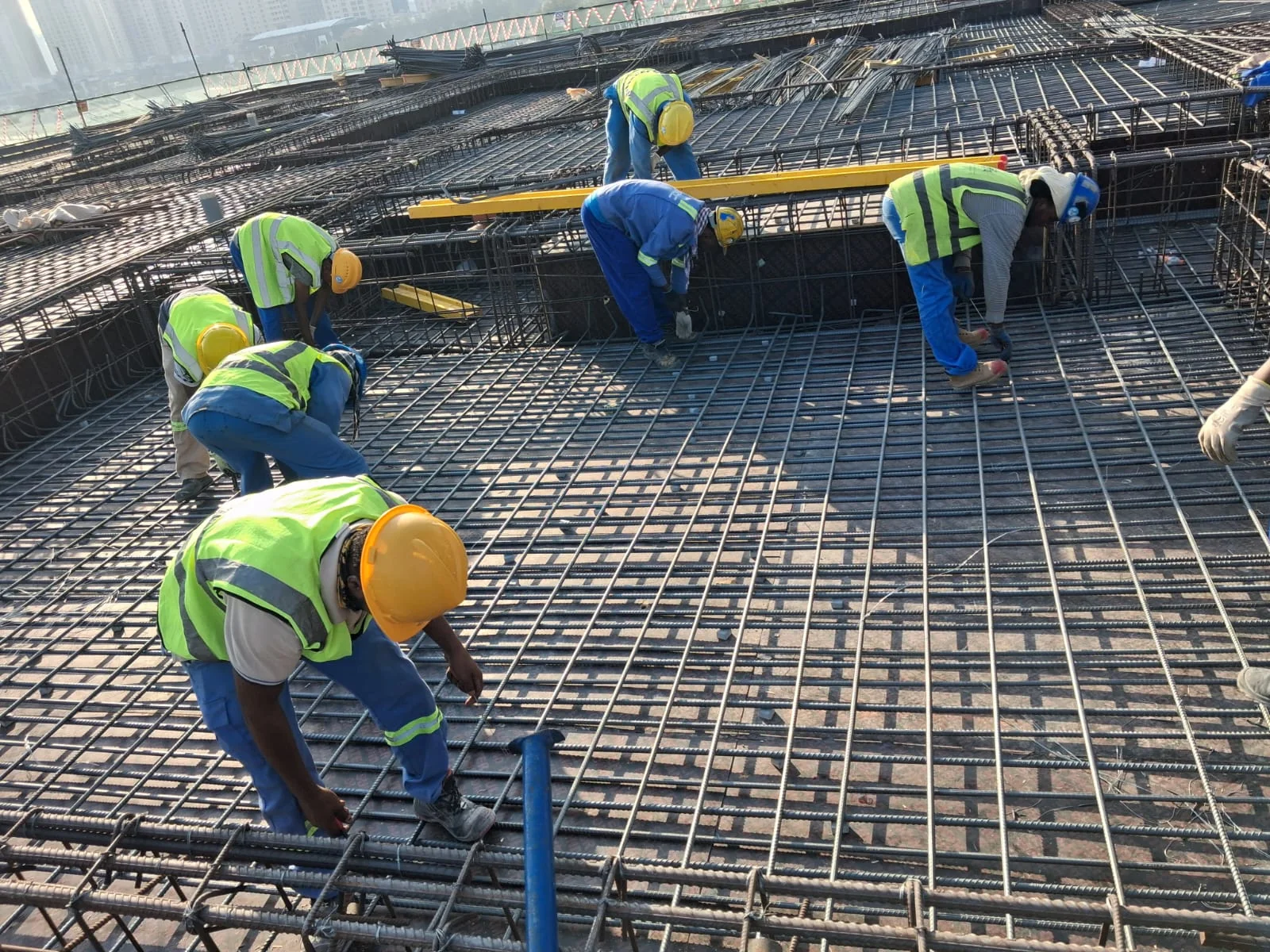 Workers handling steel reinforcement on site